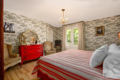 a bedroom with a bed and a red dresser and a window at The Old Bank House in Niagara on the Lake