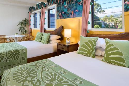um quarto de hotel com duas camas e uma mesa em MaKai Sunset Inn em Lahaina