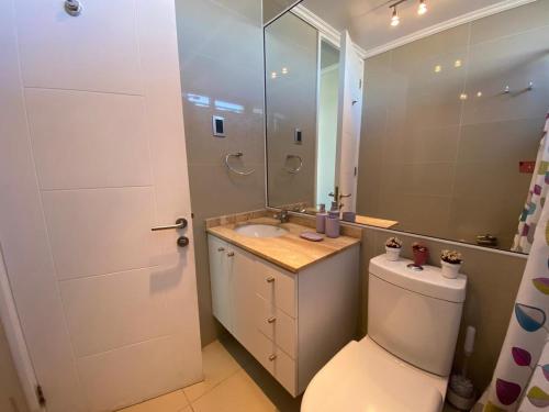 a bathroom with a toilet and a sink and a mirror at Departamento Jardín del Mar, Spa y Resort in Coquimbo