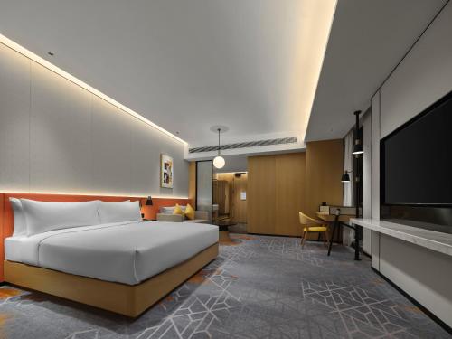 a hotel room with a bed and a flat screen tv at Hilton Garden Inn Jiaxing Xiuzhou in Jiaxing