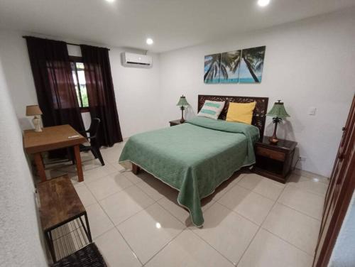 a bedroom with a bed with a green blanket and a desk at Golf Beach House w/ Pool (5 min. walk to beach!) in Tambor