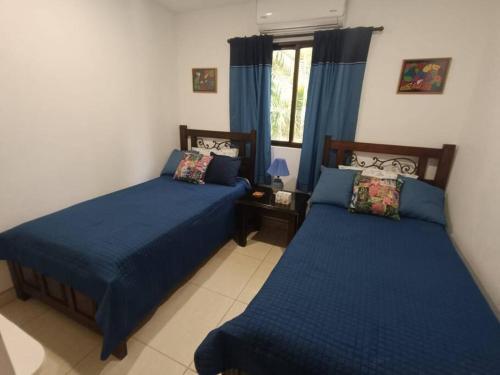 um quarto com 2 camas com lençóis azuis e uma janela em Golf Beach House w/ Pool (5 min. walk to beach!) em Tambor