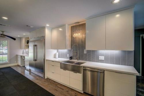 uma cozinha com armários brancos e um frigorífico de aço inoxidável em Beautiful 4 bedroom home with Pool, Hot Tub & More em Tyler