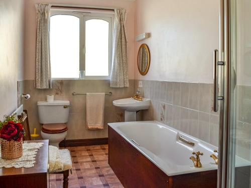 uma casa de banho com uma banheira, um WC e um lavatório. em Rose Rigg Cottage em Kirklinton