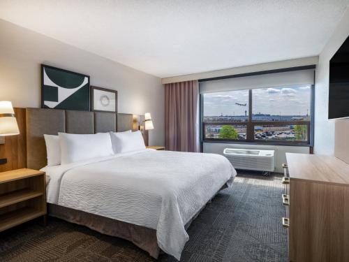 a hotel room with a bed and a large window at Staybridge Suites Chicago O'Hare - Rosemont by IHG in Rosemont