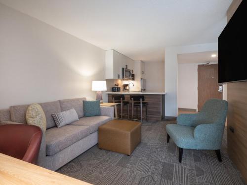 a living room with a couch and chairs and a kitchen at Staybridge Suites Chicago O'Hare - Rosemont by IHG in Rosemont