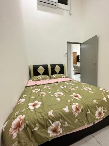 a bedroom with a bed with a green blanket with pink flowers at Aisy Guest House - MUSLlM Only in Kangar