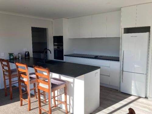 eine Küche mit weißen Schränken und einer schwarzen Arbeitsplatte in der Unterkunft Brand new family home in Richmond