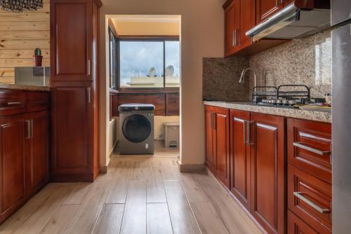 a kitchen with wooden cabinets and a washing machine at Loft con terraza en Santo Domingo in La Estrella