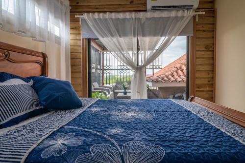 a bedroom with a bed with a blue comforter and a window at Loft con terraza en Santo Domingo in La Estrella