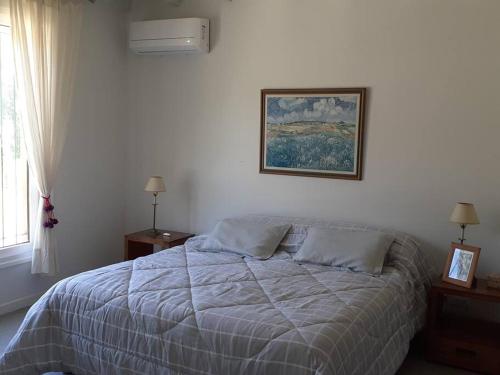 a bedroom with a bed and a picture on the wall at Casa de Campo con Bosque y Pileta in Tandil