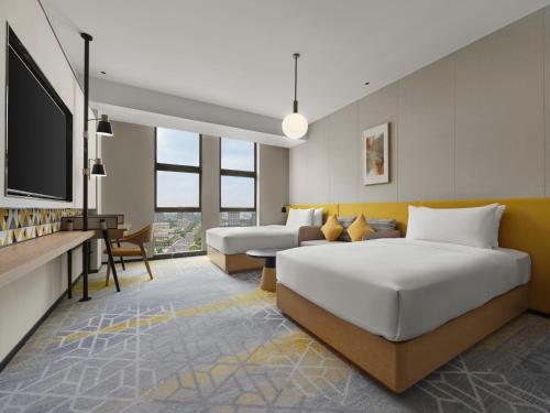 a hotel room with two beds and a tv at Hilton Garden Inn Jiaxing Xiuzhou in Jiaxing