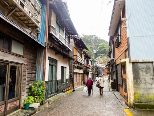 two people walking down a street in an alley at Stay Do in Oshima