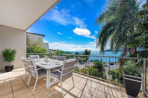 a table and chairs on a balcony with a view of the ocean at Whitsunday Beachfront Apartment on Broadwater in Airlie Beach
