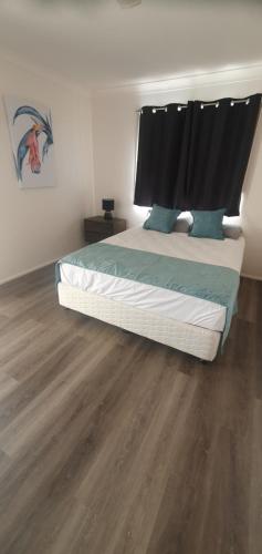 1 dormitorio con 1 cama y suelo de madera en Burketown Pub en Burketown