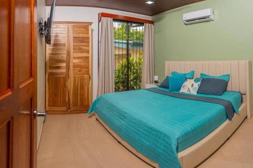 a bedroom with a bed with blue sheets and a window at Villa Aurora with Jacuzzi in La Fortuna in Fortuna