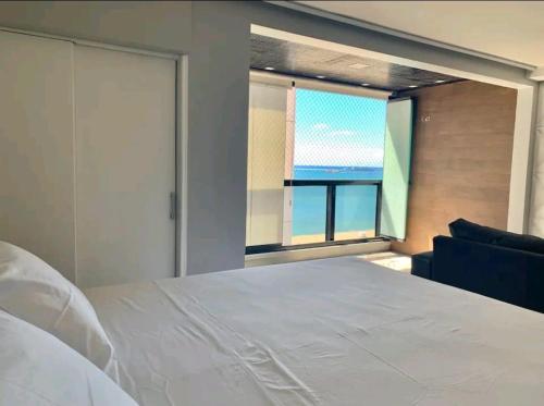a bedroom with a white bed and a large window at Atlântico Vista Mar Deluxe in Fortaleza