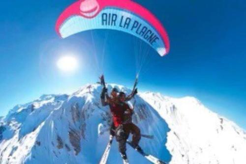 a person is flying in a parachute over a mountain at Appartement BELLE PLAGNE et PARKING in Belle Plagne