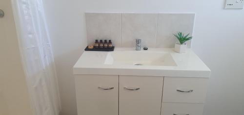 un lavabo blanco en un baño blanco con una planta en Burketown Pub en Burketown