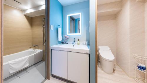 a bathroom with a white sink and a tub and a toilet at Hotel Dorf Shizuoka in Shizuoka