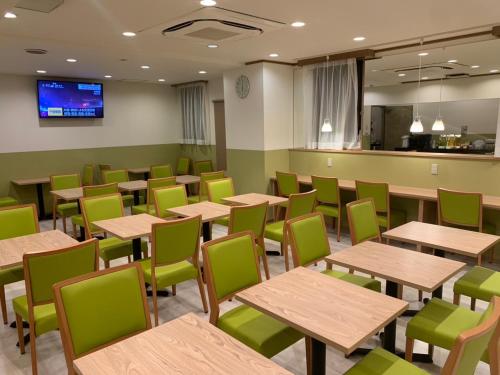 a dining room with wooden tables and green chairs at Hotel Dorf Shizuoka in Shizuoka