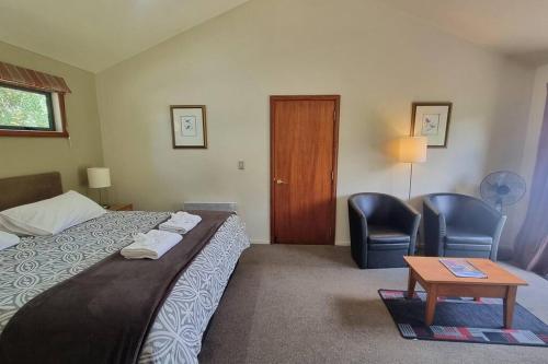 a hotel room with a bed and two chairs and a table at 18 Jollies Pass Road - Garden Studio 346 in Hanmer Springs