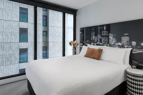 a bedroom with a large white bed and a large window at Imagine Southbank in Melbourne