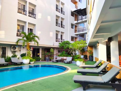 a swimming pool in the courtyard of a building with lounge chairs at The Chanthong Residence and Hotel Pattaya in Pattaya South