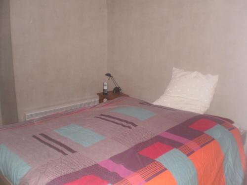 uma cama com um cobertor colorido e uma almofada em Maison Belz, 3 pièces, 4 personnes - FR-1-397-19 em Belz