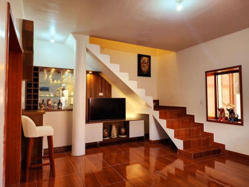 a living room with a staircase and a television at El Rey Lobo Casa de Campo Valle Sagrado in Urubamba