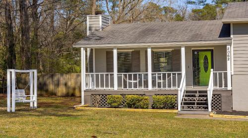 a small house with a white porch and a green door at GoodKarma Rentals Spacious and Comfy Abode in Austell in Austell