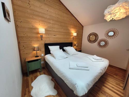 1 dormitorio con 1 cama blanca grande y pared de madera en Appartement Les Gets, 2 pièces, 4 personnes - FR-1-598-145, en Les Gets
