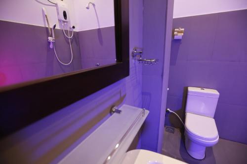 a purple bathroom with a toilet and a mirror at J Hotel in Jaffna