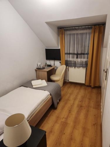 1 dormitorio con 1 cama y escritorio con silla en Zajazd FENIKS en Lubaczów