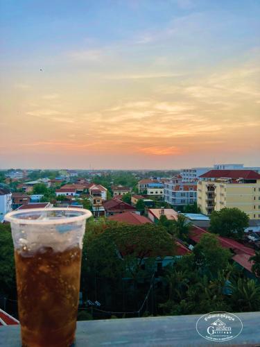 a glass of beer sitting on a table with a view of a city at Garden Village Guesthouse & Pool Bar in Siem Reap