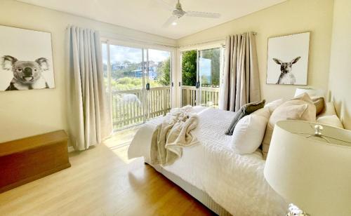a bedroom with a white bed and a window at Shore Bird On Moreton in Tangalooma