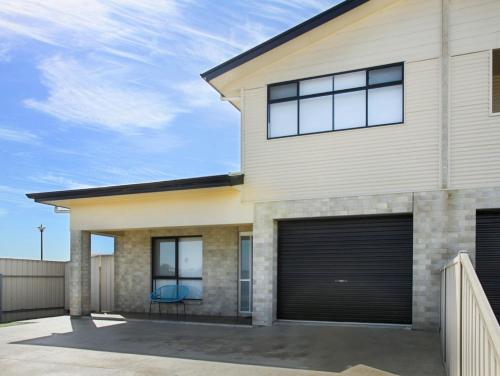 a house with two garage doors and a fence at Blue Door Retreat in Edithburgh