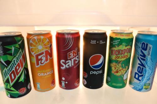 a row of six cans of soda in a refrigerator at Cahaya Homestay Tanjung Malim in Ulu Bernam