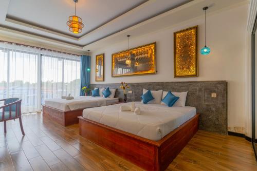 シェムリアップにあるAngkor Rithy Boutiqueのベッド2台とテーブルが備わるホテルルームです。