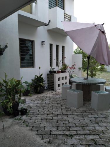 a patio with a table and an umbrella in front of a house at Departamentos de la Reina Roja in Palenque
