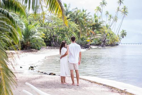 a couple standing on the beach looking at the water at Opoa Beach Hotel in Opoa