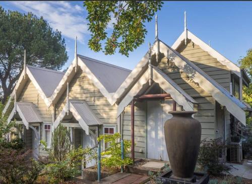 a house with a large vase in front of it at Olive Tree Cottage in Central Tilba