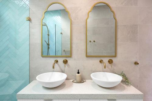 a bathroom with two sinks and two mirrors at Ubuntu by Experience Jervis Bay in Vincentia