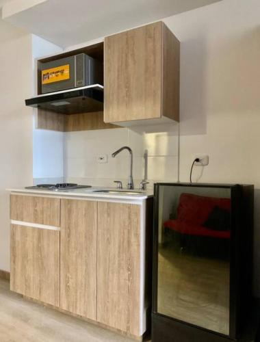 a kitchen with wooden cabinets and a sink and a microwave at Cama Queen, Vista a las Montañas in Manizales