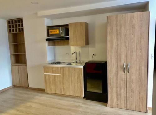 a kitchen with wooden cabinets and a sink and a microwave at Cama Queen, Vista a las Montañas in Manizales