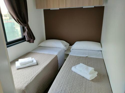 two beds in a small room with towels on them at Garda Di Vino Agricamping & Wine Shop Lazise in Ronchi