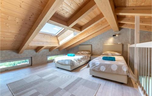 トレモージネ・スル・ガルダにあるCasa Nonno Bepiの木製天井の屋根裏部屋のベッドルームにベッド2台が備わります。
