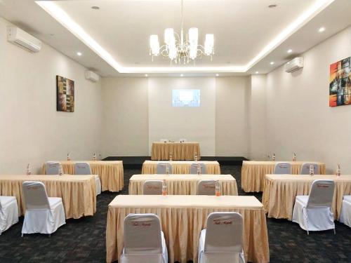 a conference room with tables and chairs and a chandelier at Kuta Majesty Hotel in Legian