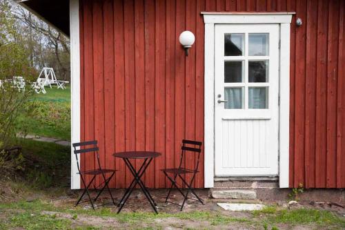 una casa rossa con due sedie e un tavolo di fronte ad una porta di Seaside Cottage in Suomenlinna a Helsinki