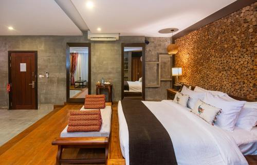 a bedroom with a large bed and a wall of logs at Cambana d'Angkor Suites in Siem Reap